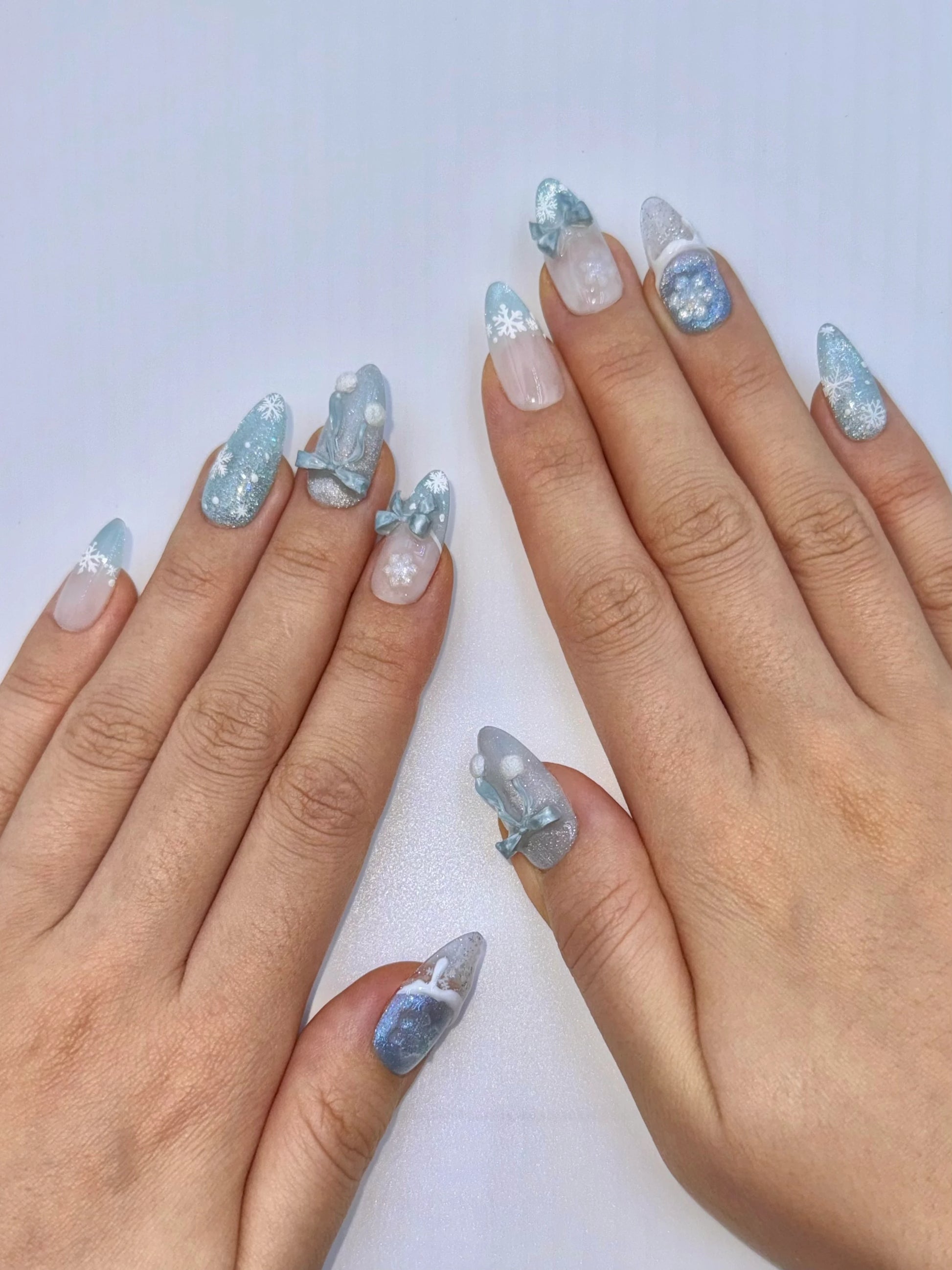 Sparkly Christmas Holiday Snowflake Bow Ribbon Almond Icy Blue Press-On Nails with Fluffy Pom-Poms, Unique Cute Girly Winter Snow Glittery Nail Art | Secure The Nails